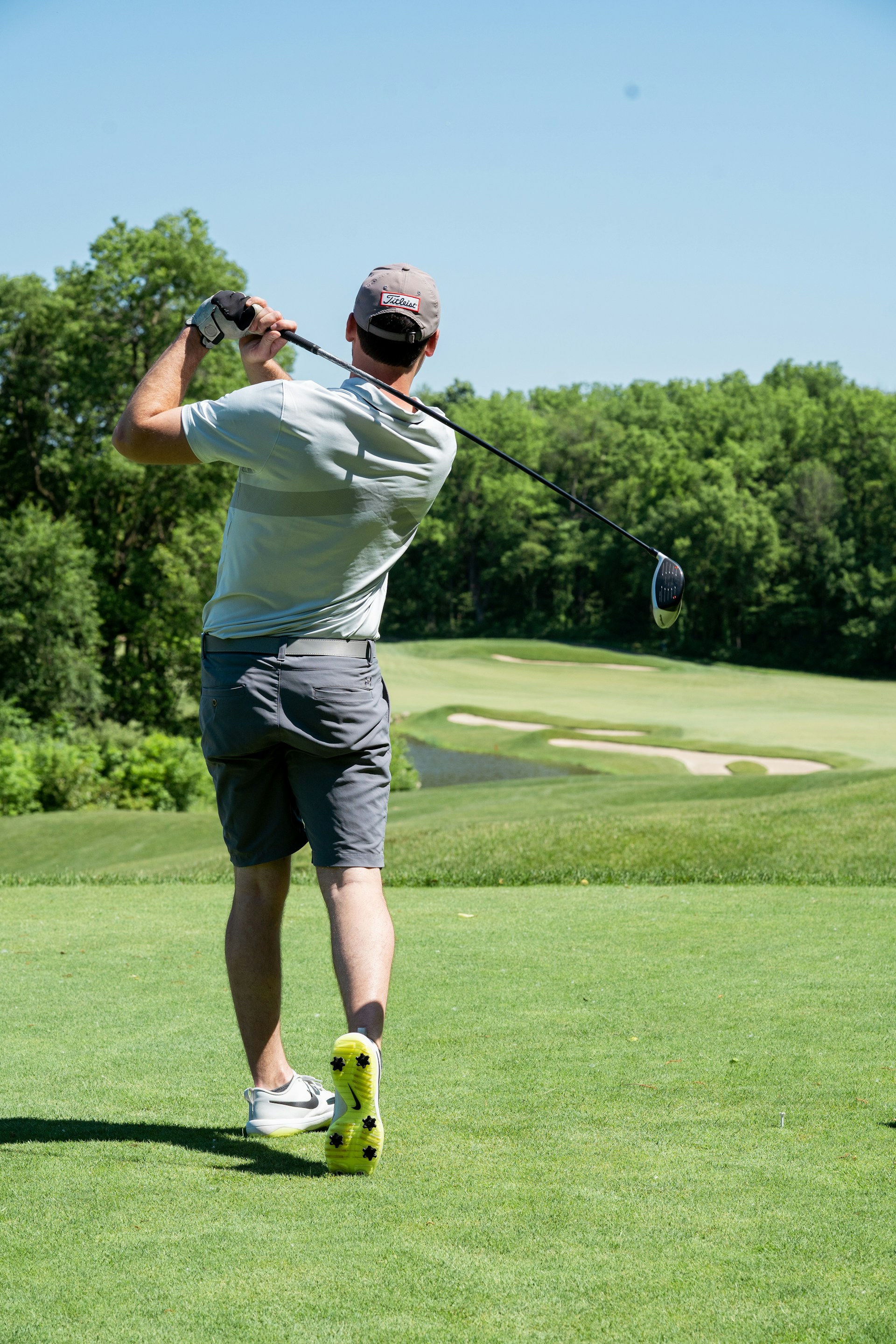 Jucător de golf pe un teren în aer liber, fotografiat din spate